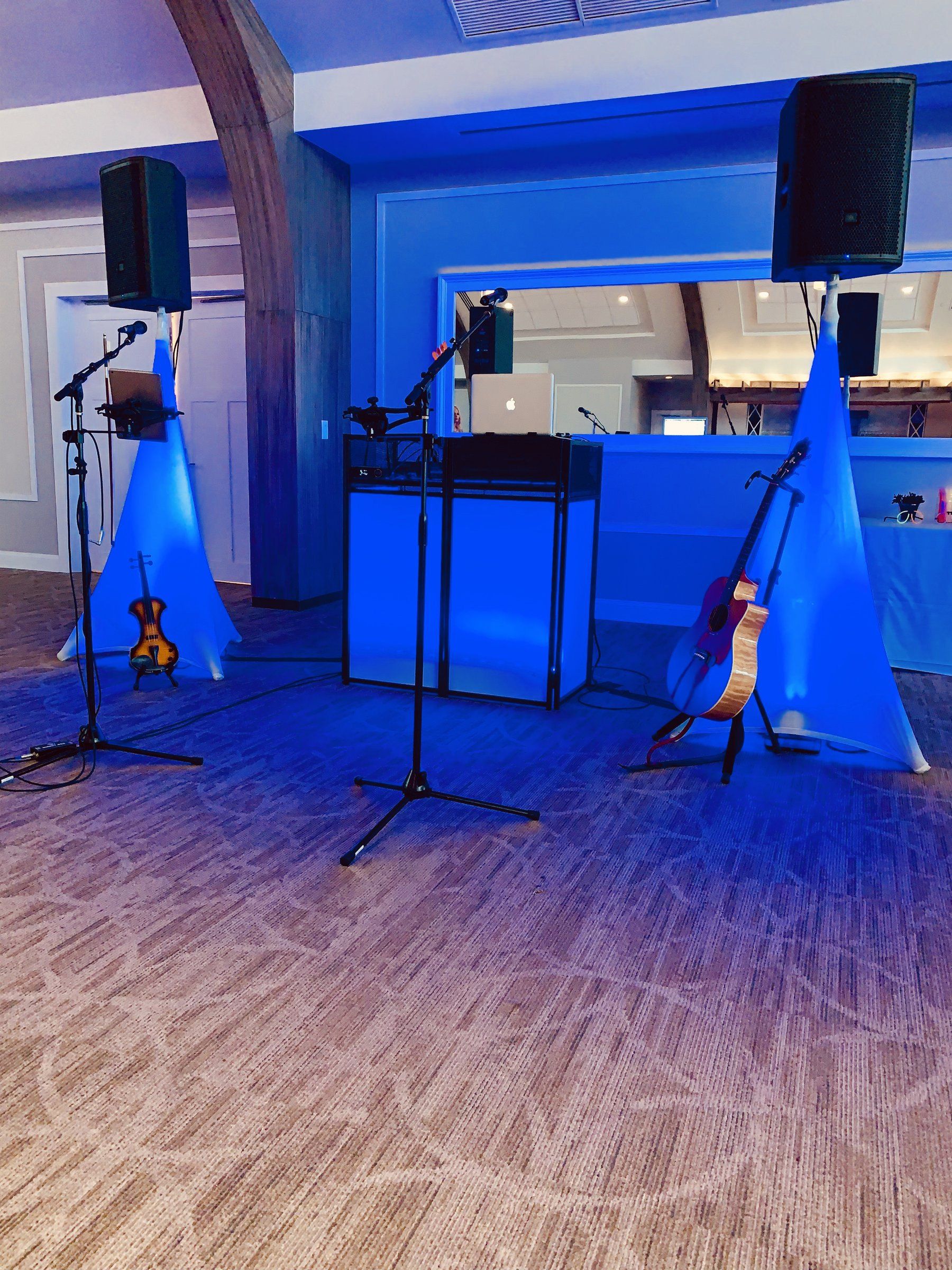 A DJ booth and speakers on stands under deep blue lighting